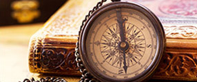 A worn compass, leaned against an ancient tome